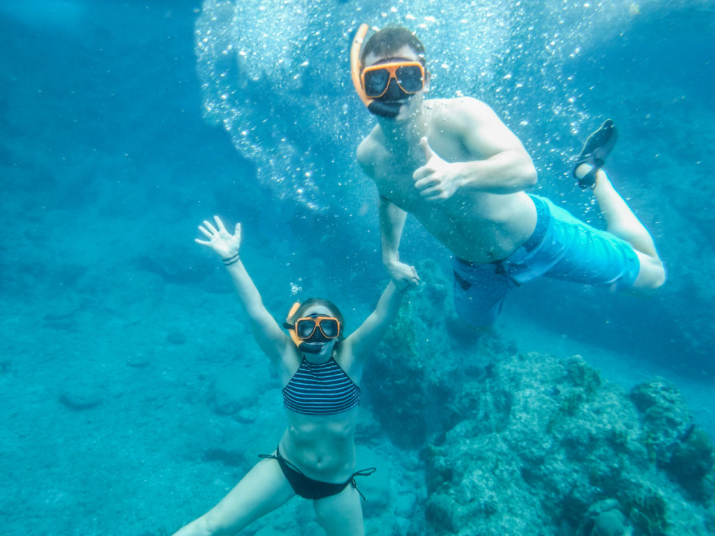 An image of a man and a woman underwater in the British Virgin Islands wearing snorkeling equipment. The image is mostly blue because of the tropical water.