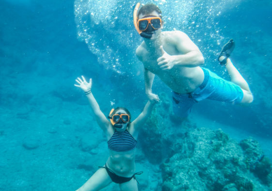 An image of a man and a woman underwater in the British Virgin Islands wearing snorkeling equipment. The image is mostly blue because of the tropical water.