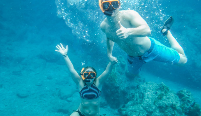 An image of a man and a woman underwater in the British Virgin Islands wearing snorkeling equipment. The image is mostly blue because of the tropical water.